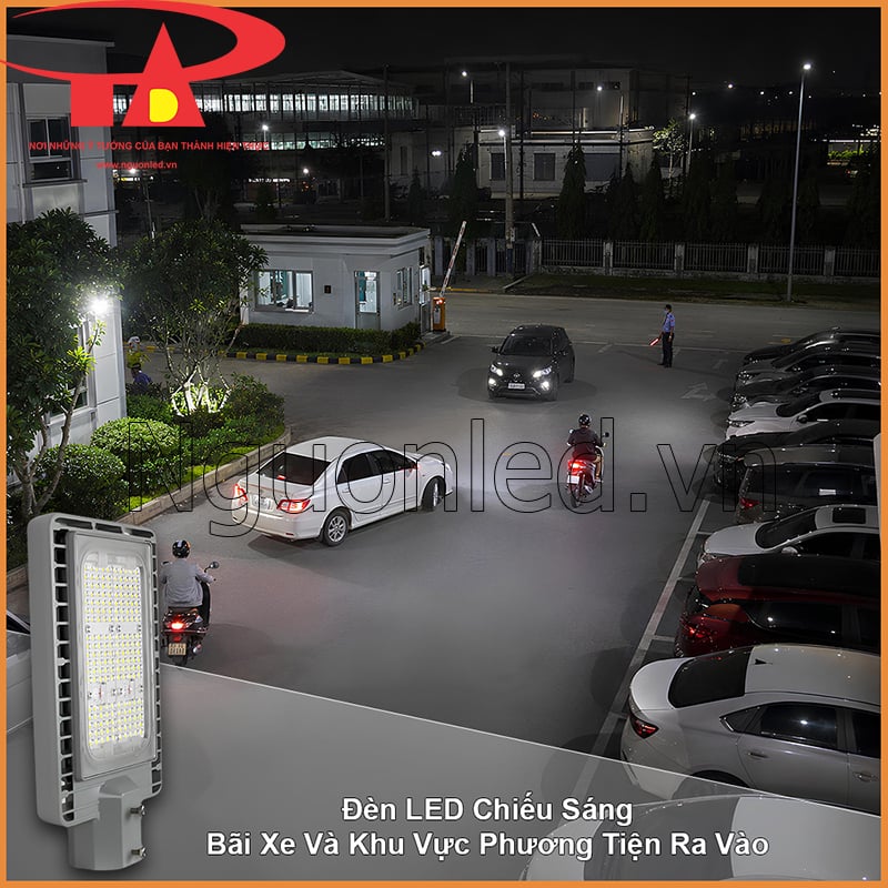 Bãi xe công ty vào ban đêm với ô tô, xe máy và khu vực phương tiện ra vào gần chốt bảo vệ