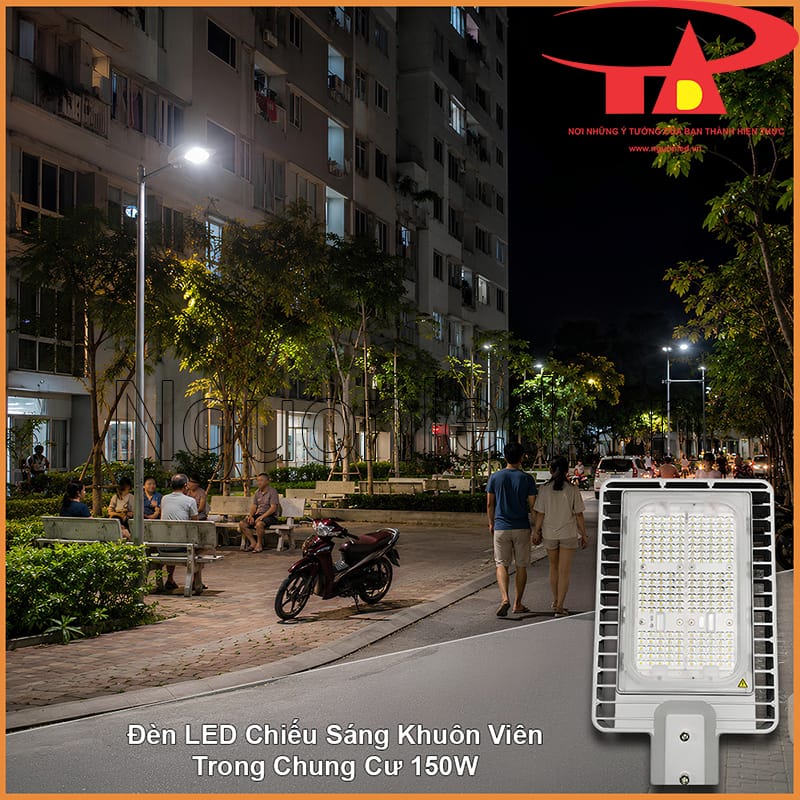 Khuôn viên chung cư vào buổi tối với người đi bộ, xe máy và đèn đường chiếu sáng lối nội bộ