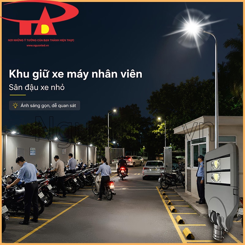 Đèn đường Philips 100W tại khu giữ xe máy nhân viên ban đêm, có dãy xe, ô tô con, chốt bảo vệ và cột đèn